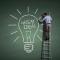 Man on ladder drawing light bulb on big blackboard